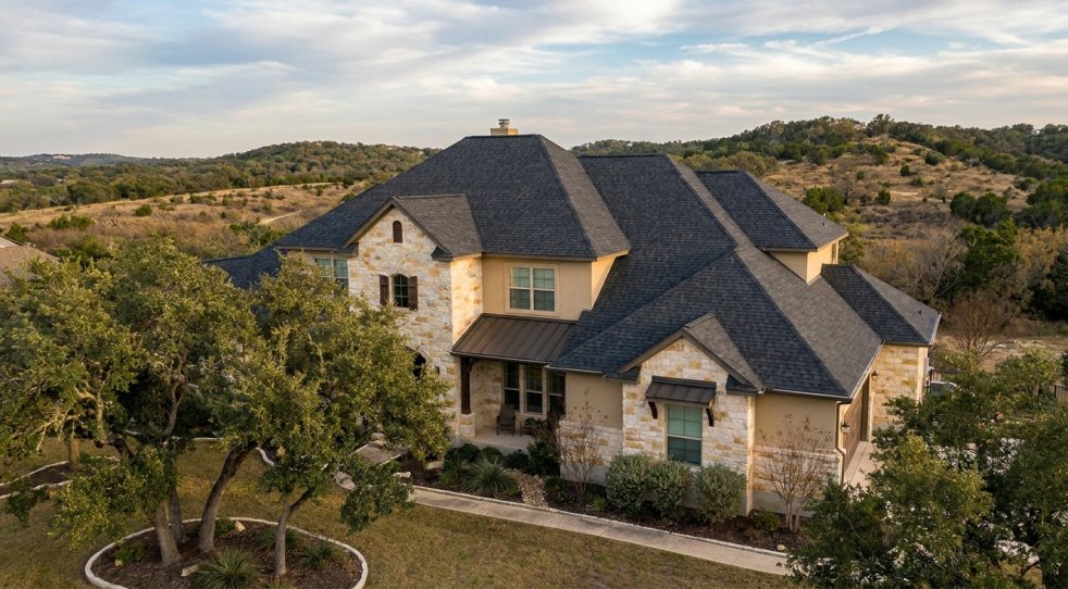 New shingle roof on a stone house in Boerne, Texas with Hill Country landscape