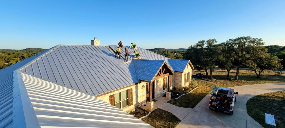 Roofers installing a metal roof on a house in the Texas Hill Country
