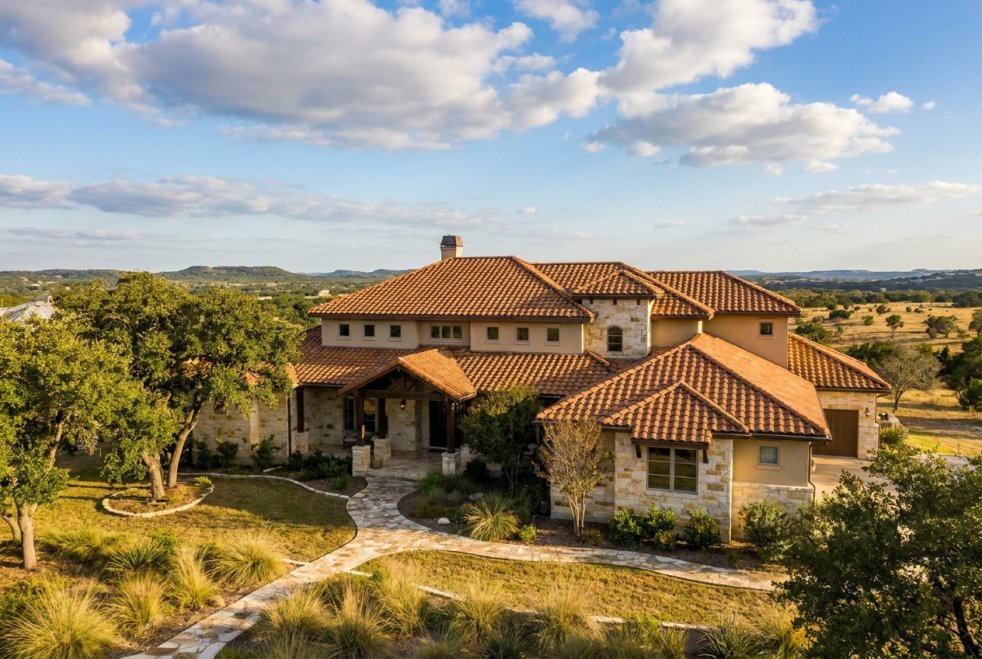 Luxury home with tile roof in Boerne, Texas, surrounded by trees and rolling hills
